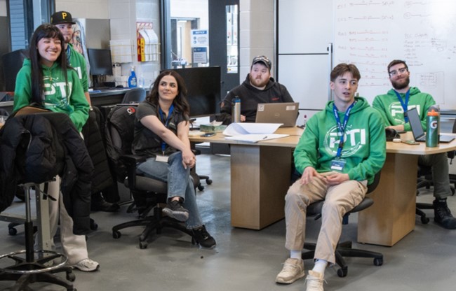 Group of students and facilitators gathered in a classroom or training lab during a collaborative learning session.