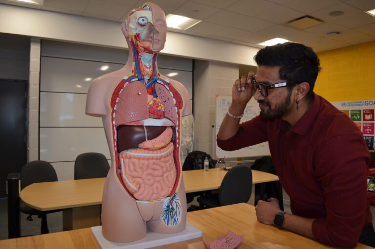 A student wearing AI glasses examines a manekin for health classes.