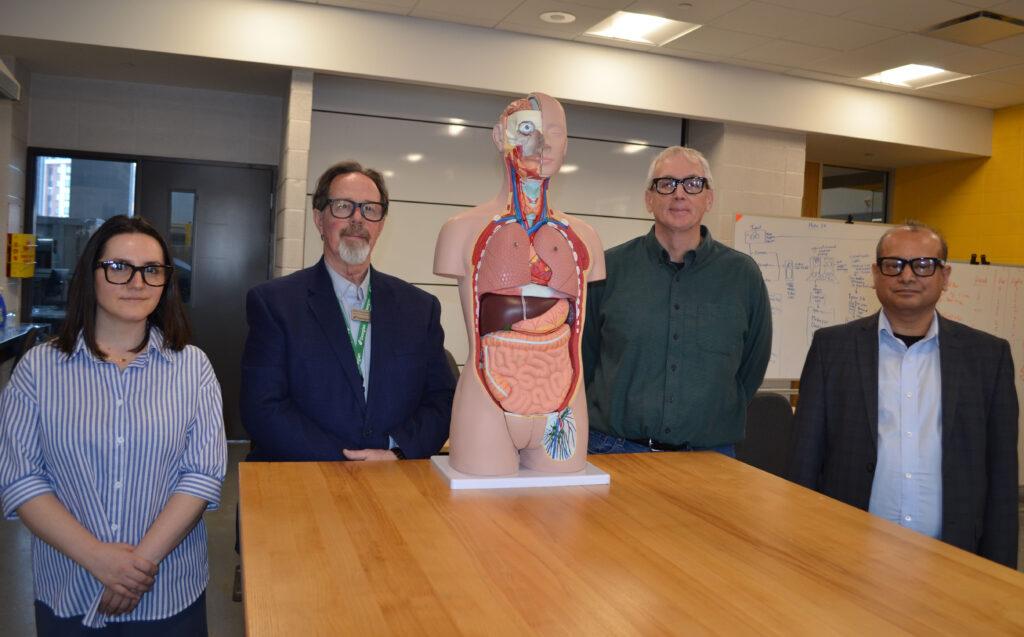 People standing in a classroom with an anatomy manekin.