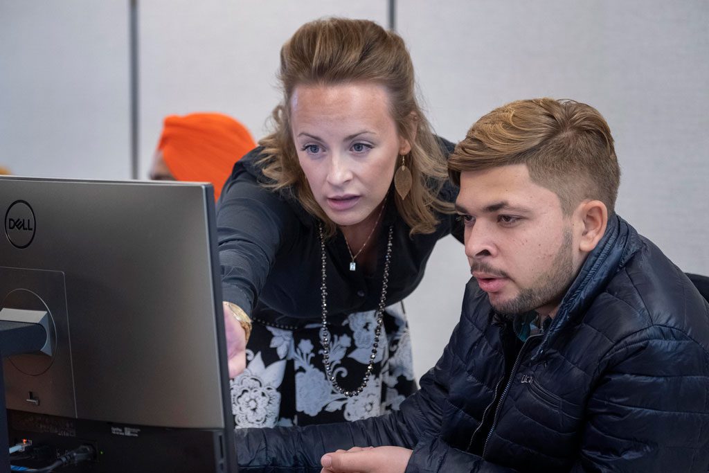female professor assisting a male student using a computer