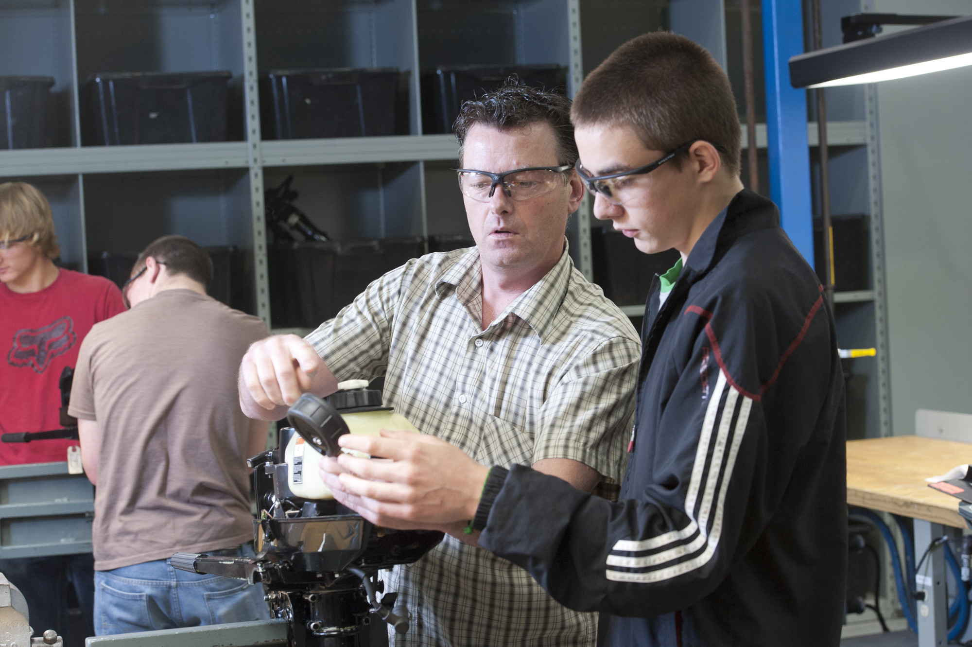 Professor in shop showing male student a part