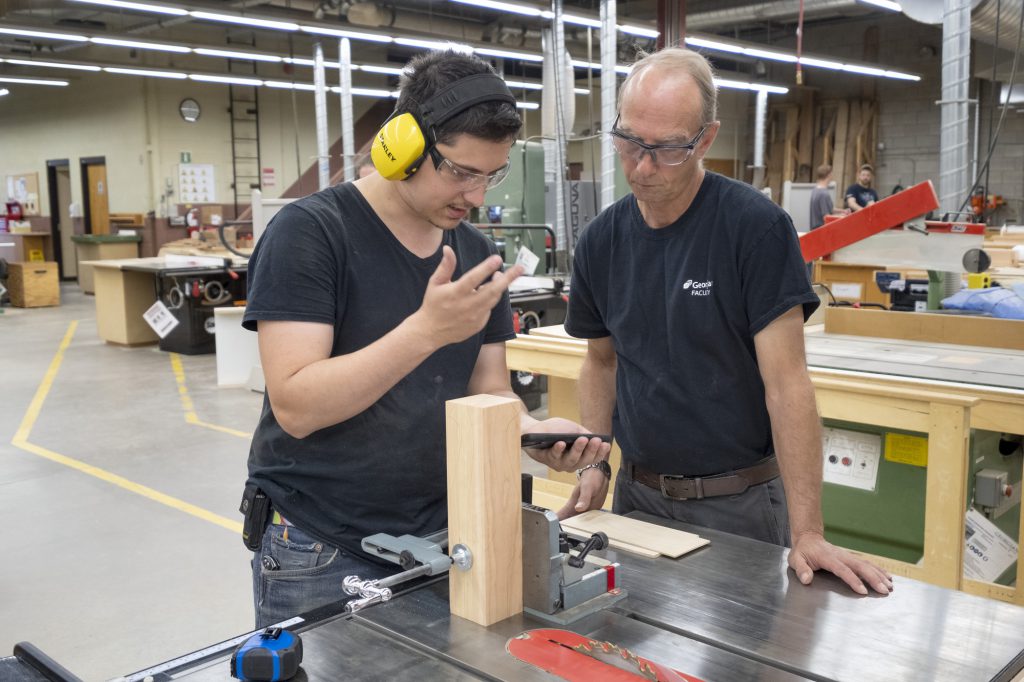 Male student and teacher working on a wood project in the shop