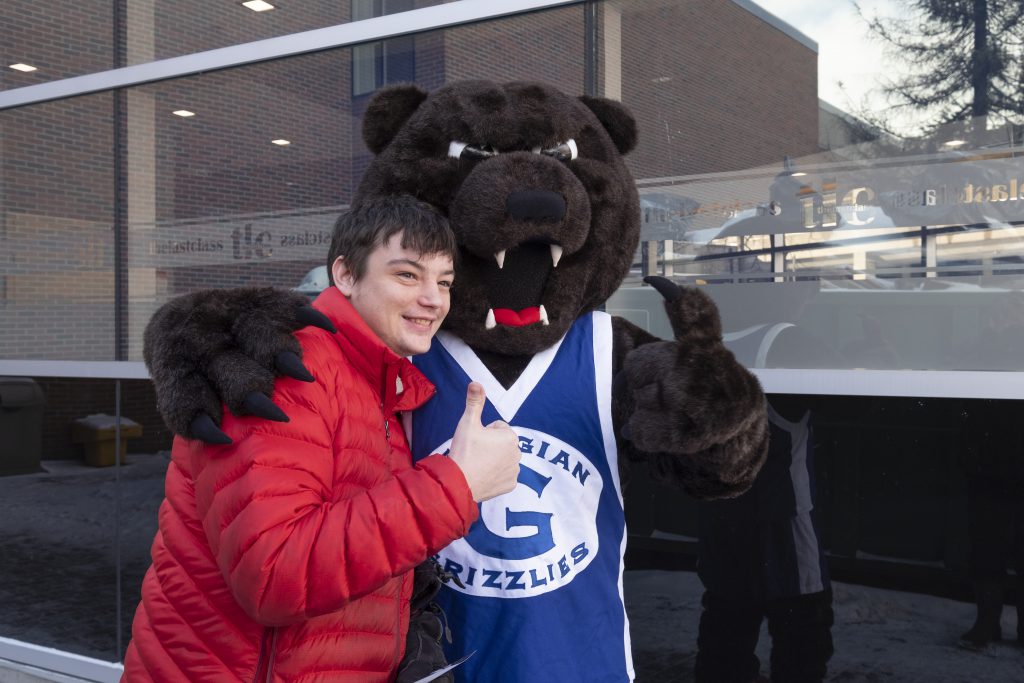Male student with mascot with their thumbs up