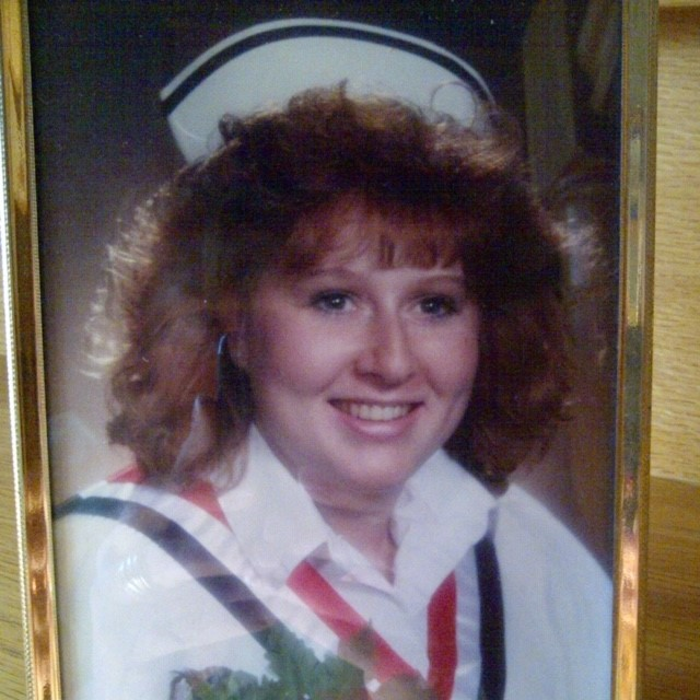 Person in a nurse's uniform smiles at the camera.