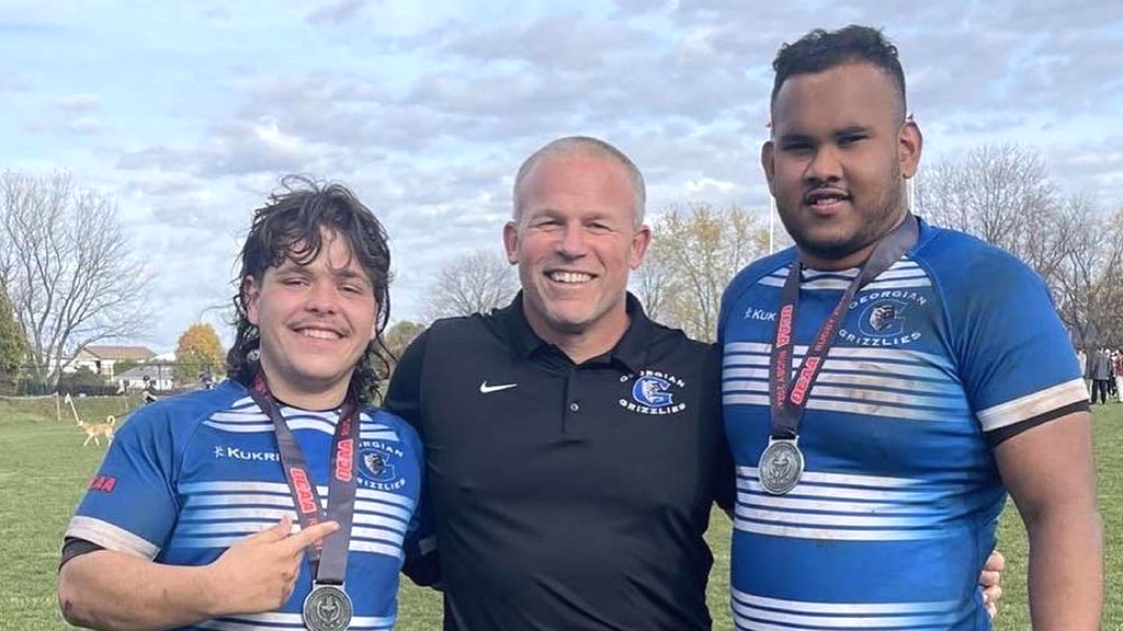 Rugby players James left and Rahal right on the field with Coach John Daggett