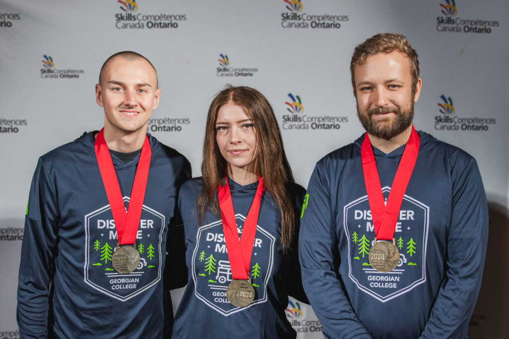 Three students wearing gold medals pose at the Skills Ontario competition.