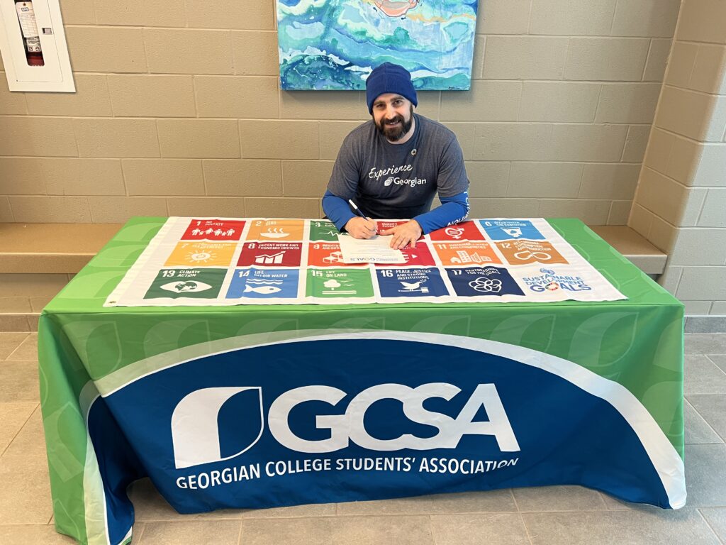 Patrick Salvagna sitting at a table signing the Sustainable Development Goals Accord.