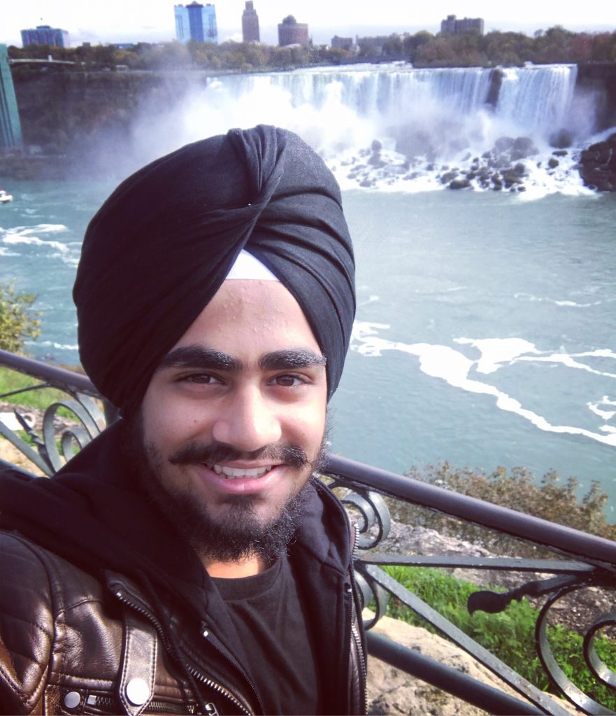 A man stands in front of Niagara Falls, smiling