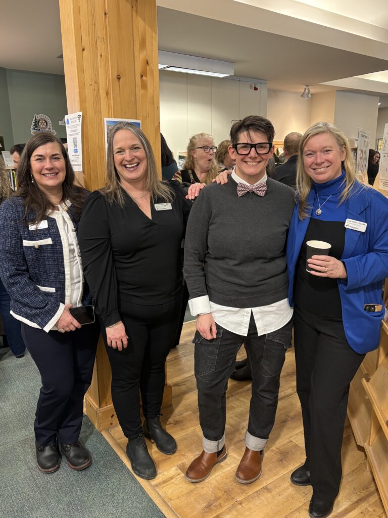 Group of 4 people standing and smiling.