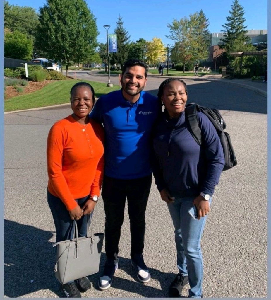 Three people stand outside on a sunny day.