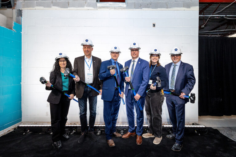 Six people wearing hard hats and holding construction equipment.