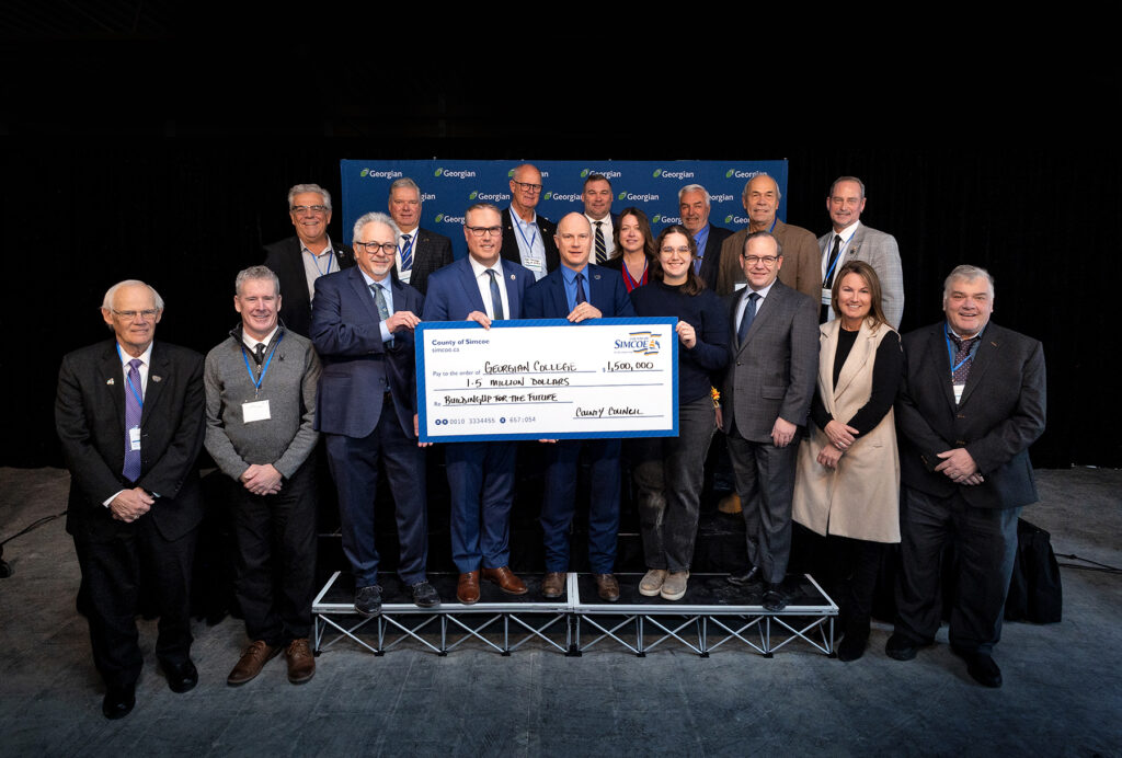 Group of people posting with large donation cheque. 