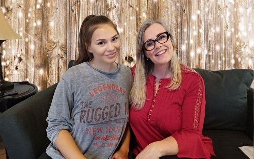 Two women sitting together on a couch.