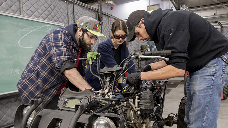 Two-male-and-one-female-student-work-on-an-ATV-in-the-Skilled-Trades-Centre