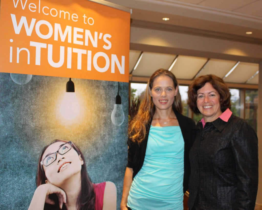 Two women standing next to a banner.