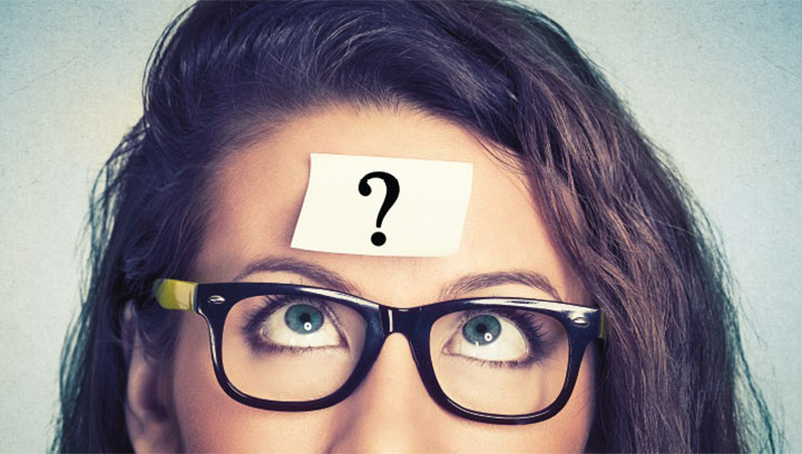 Young female student with brown hair, glasses and a question mark on her forehead