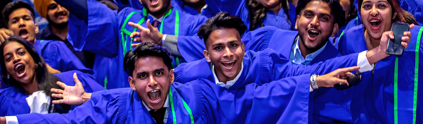 Several graduates smiling and cheering at a convocation celebration
