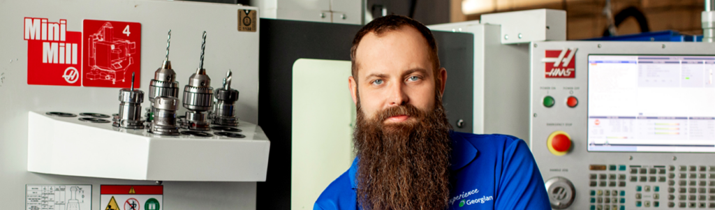 Brett Austin, Georgian alumnae stands beside machinery in the Centre for Skilled Trades