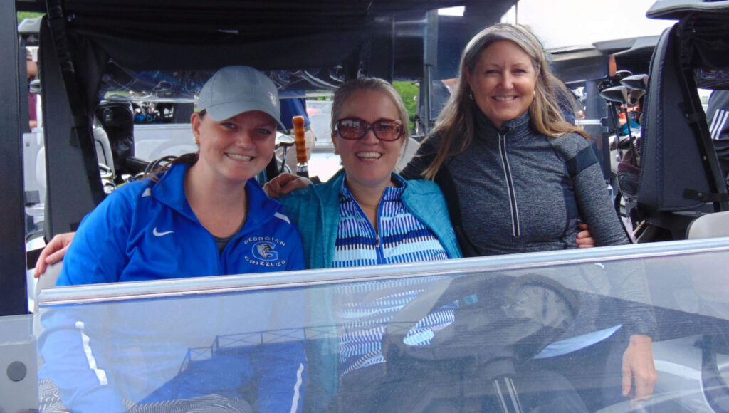 three smiling women golfers in a cart