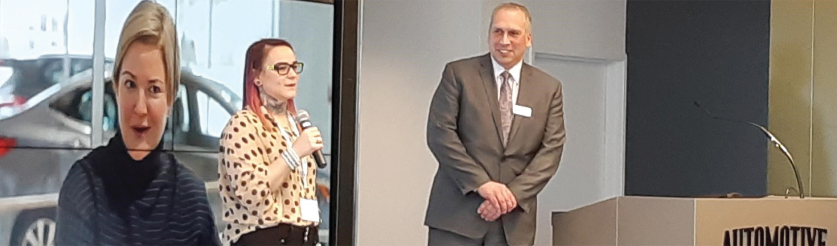 A Georgian alumni speaks while holding a microphone, as a persons stands next to them while smiling