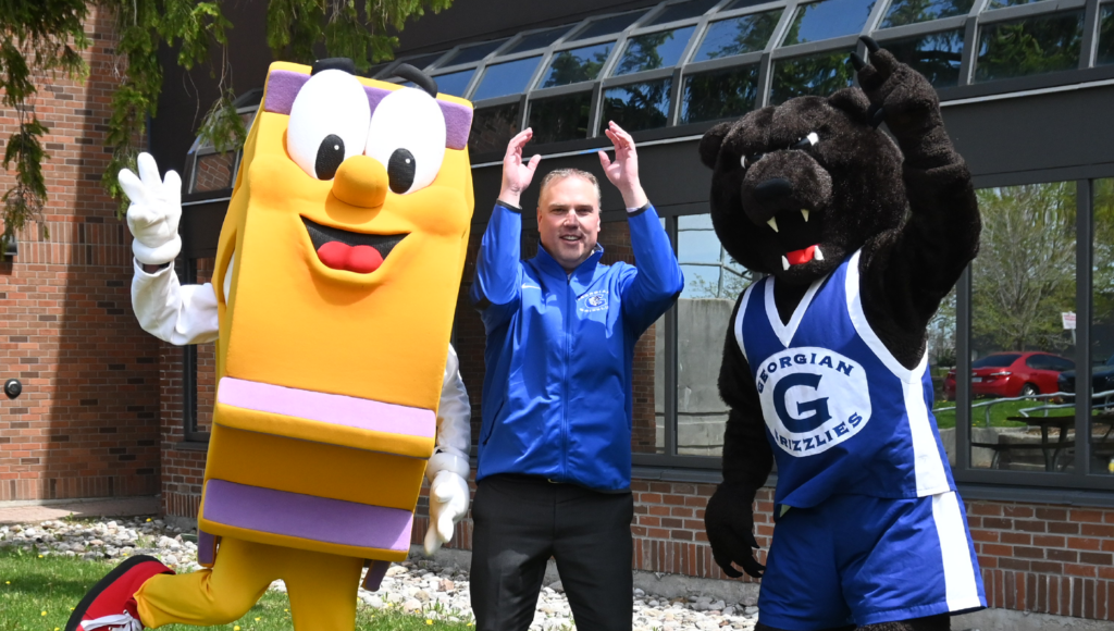 Georgian College President and CEO Kevin Weaver (centre), Sprocket (left), and Growler (right) cheering outside of Georgian College building