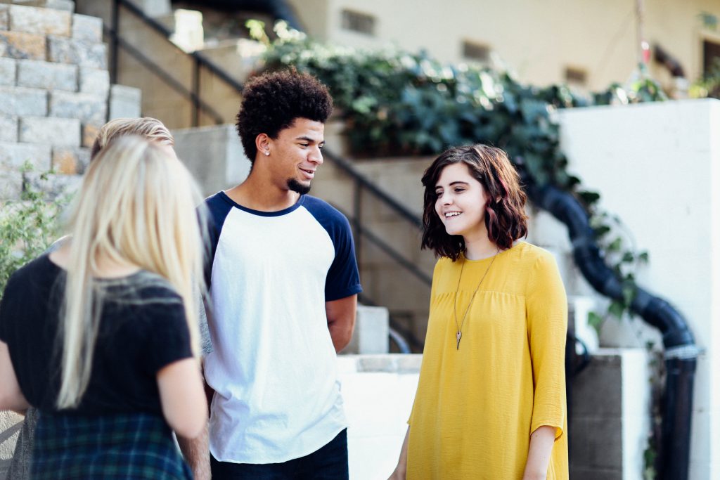 2 young females and 1 young male talking to each other