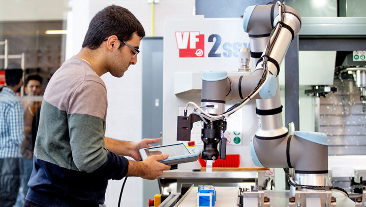 An AI technologist with short, brown hair and glasses using a controller to program a machine with artificial intelligence