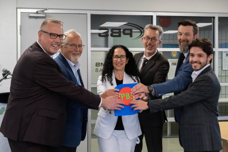 A group stand together smiling for a photo.