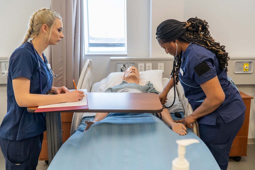 two female BSCN nursing students conducting a vital sign assessment on a patient simulator in Georgian College's nursing lab
