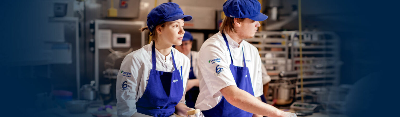 Georgian College Baking and Pastry arts students wearing uniforms, aprons, hair nets and hats making pastry in the baking lab