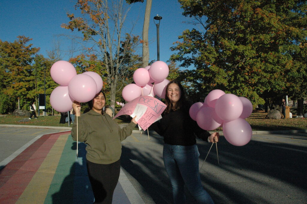 Two people holding pink balloons. 