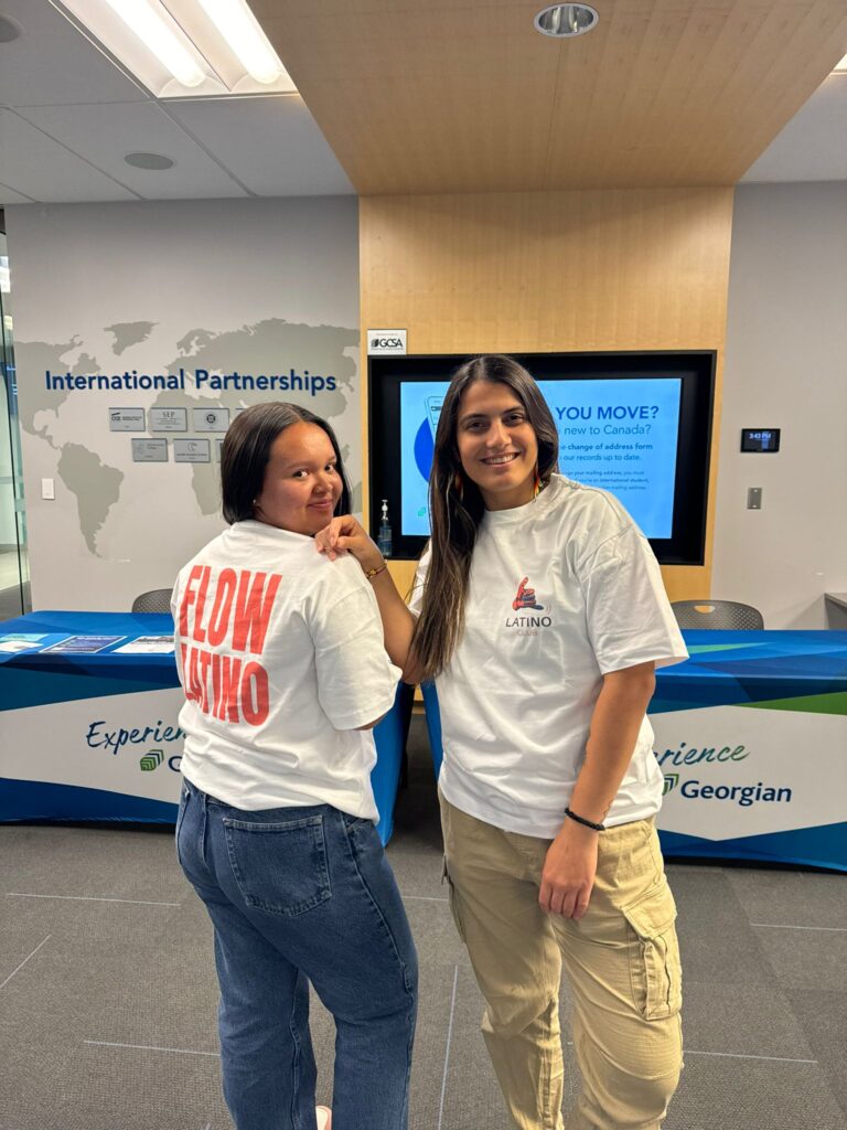 Two people wearing T-shirts reading "Latino Club" smile at the camera. 