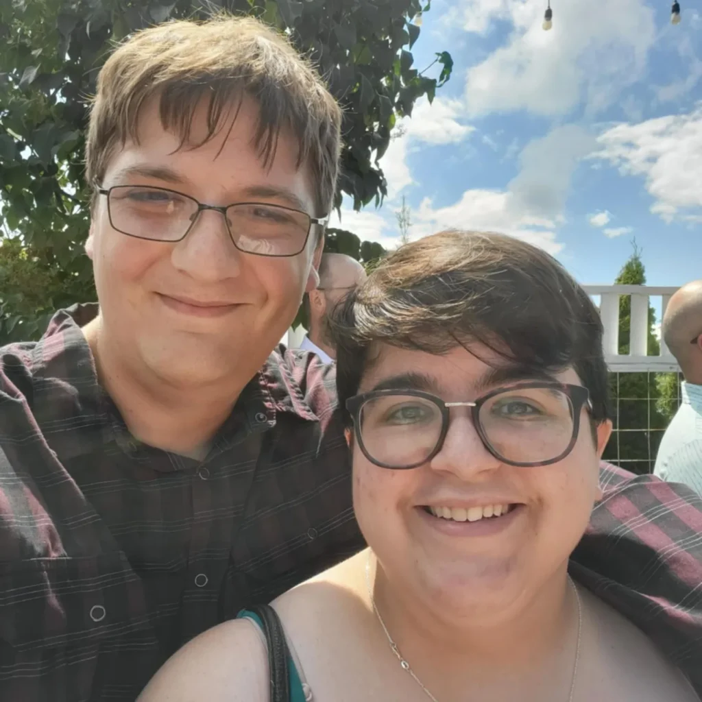 Two people take a selfie together while standing outside.