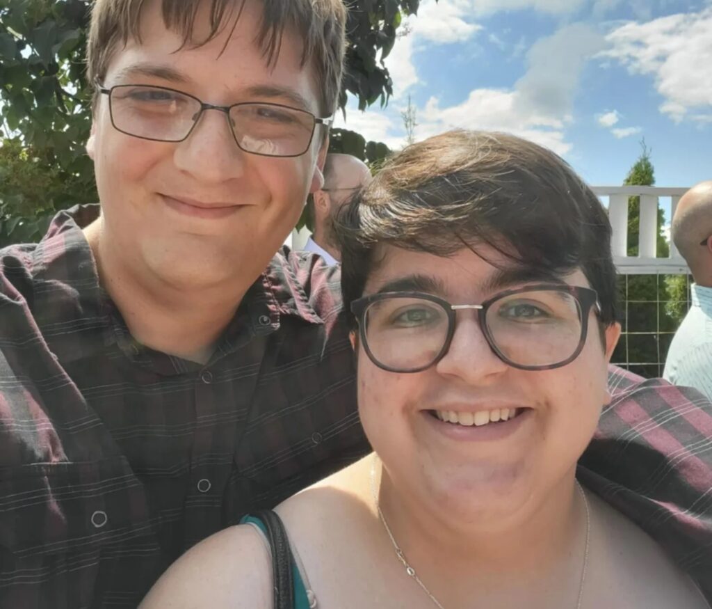 Two people take a selfie together while standing outside.