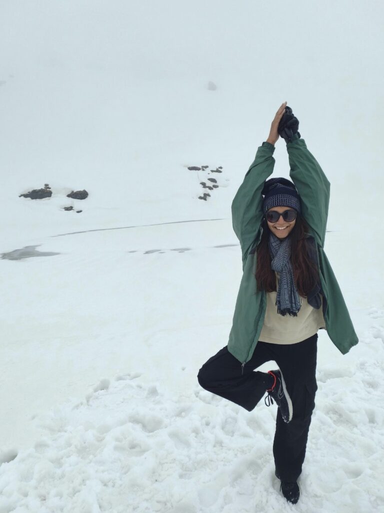 A person stands outside in the snow and does a yoga pose. 