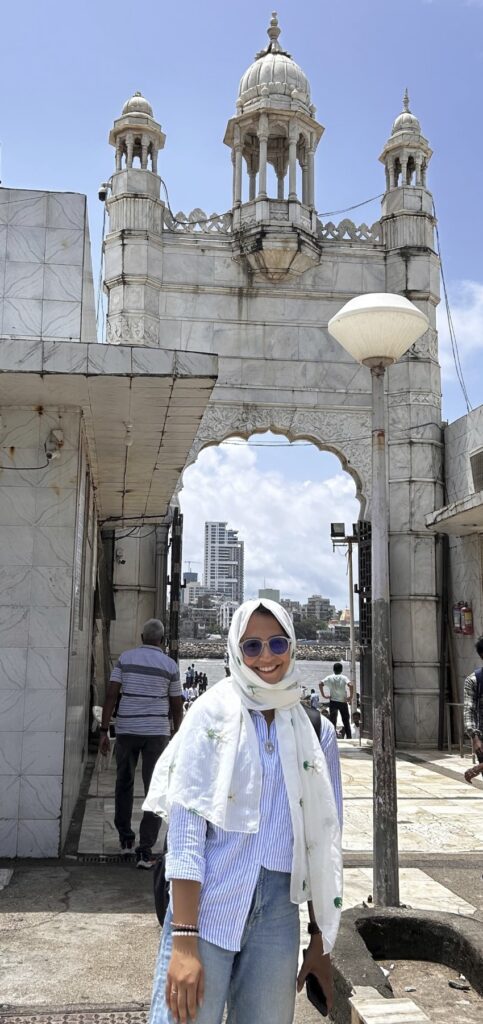 A person stands in front of a cityscape with a large archway.