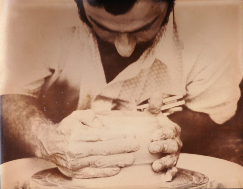 An old photo of a person shaping a ceramic artwork.