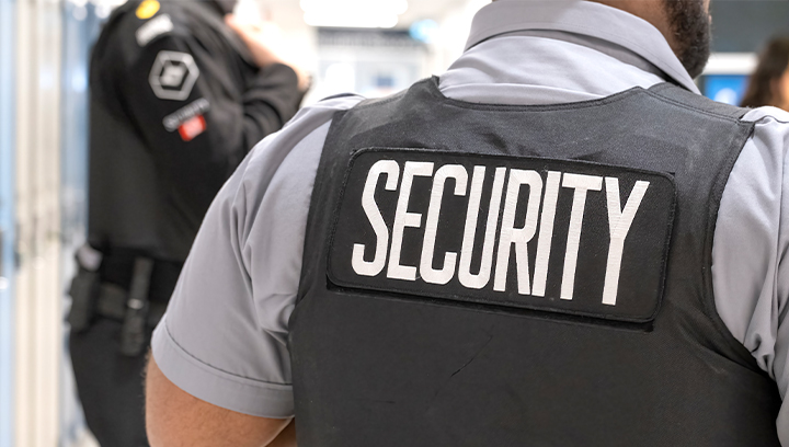 the back of a security guard in uniform, featuring a SECURITY badge on the back of a black vest