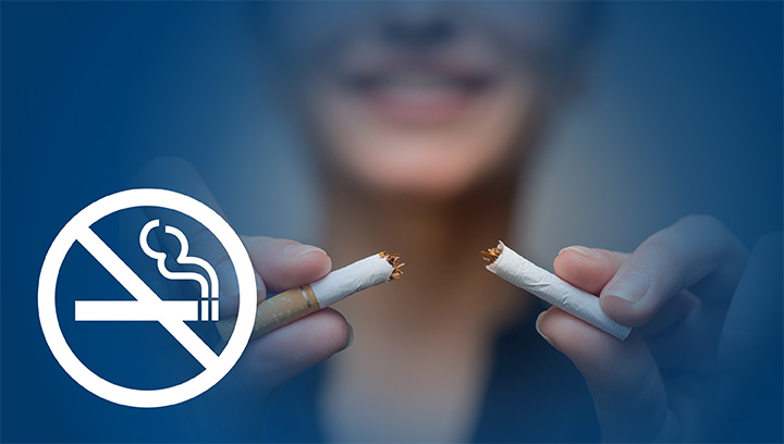 A person holding a cigarette that has been snapped in half, while smiling in the background, with an icon indicating no smoking allowed