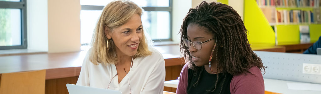 Two people sitting at a desk working on a laptop