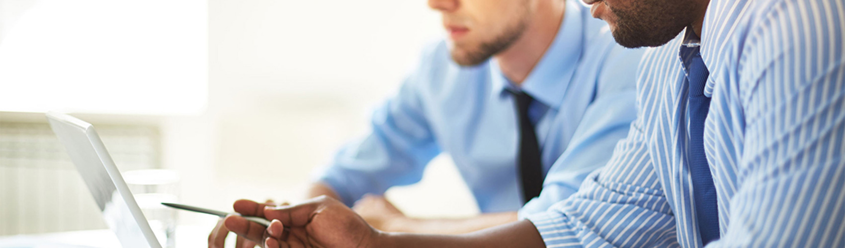 Two people in business attire looking at a computer screen