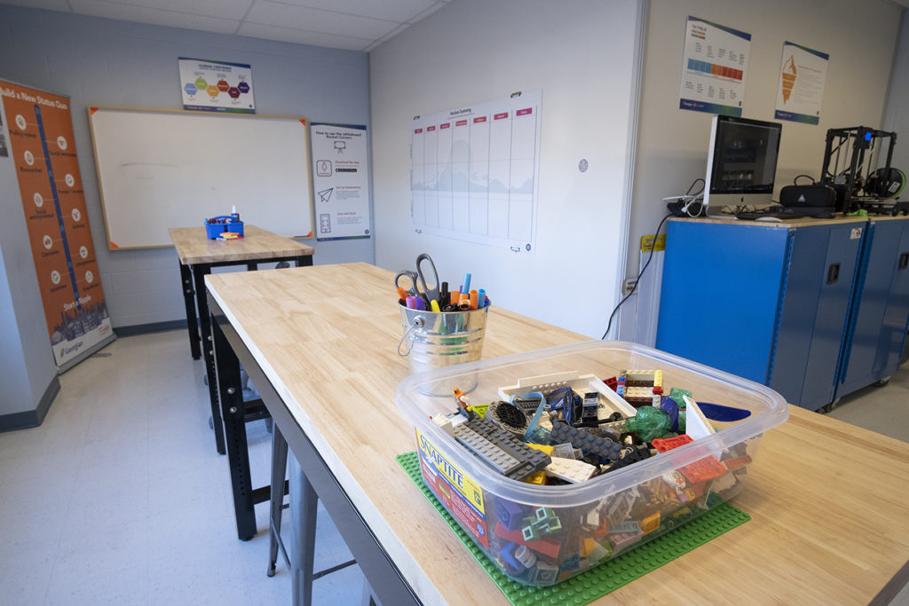 a classroom with lockers, two tables, markers, scissors and other supplies
