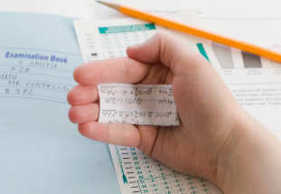 Hand holding a cheat sheet paper secretively..
