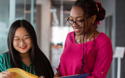 Image of two students interacting while looking at a book