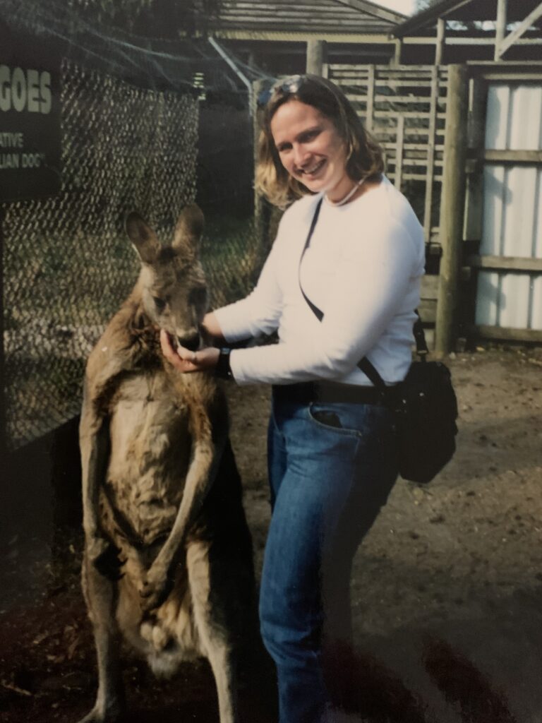 A person stands outside next to a kangaroo.