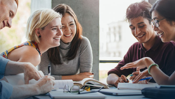 Four College Foundations students sitting at a table together collaborating on an assignment