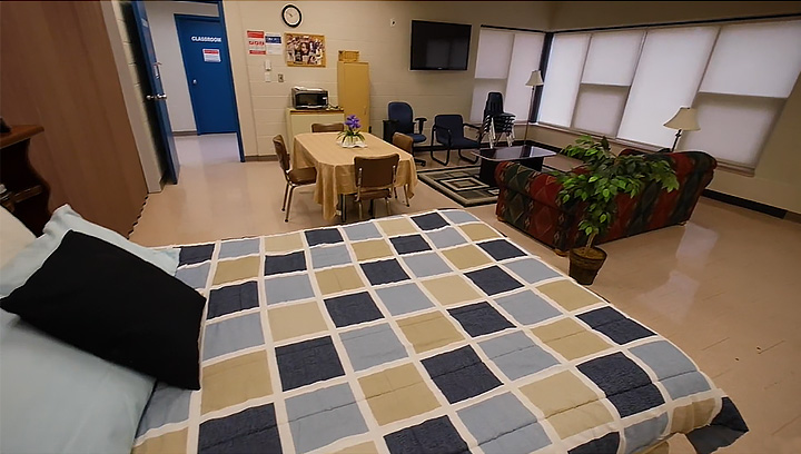 Apartment lab at the Georgian College Orillia Campus, featuring a bed, couch, coffee table, TV, dining room table and chairs, and other furnishings