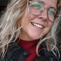 Community and Justice Services graduate Bailey Swanton with blonde hair and glasses smiling