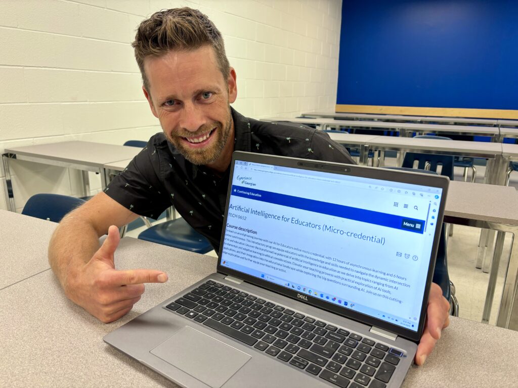 A person sits at a table behind a laptop open to a screen reading: Artificial Intelligence for Educators (Micro-credential). 