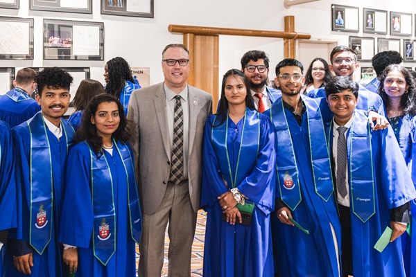 President and CEO Kevin Weaver posing with a group of Georgian students in their gowns at convocation